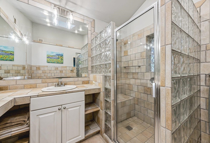 Bathroom featuring a glass block shower enclosure with a built-in bench, a glass shower door, and full tile surrounds