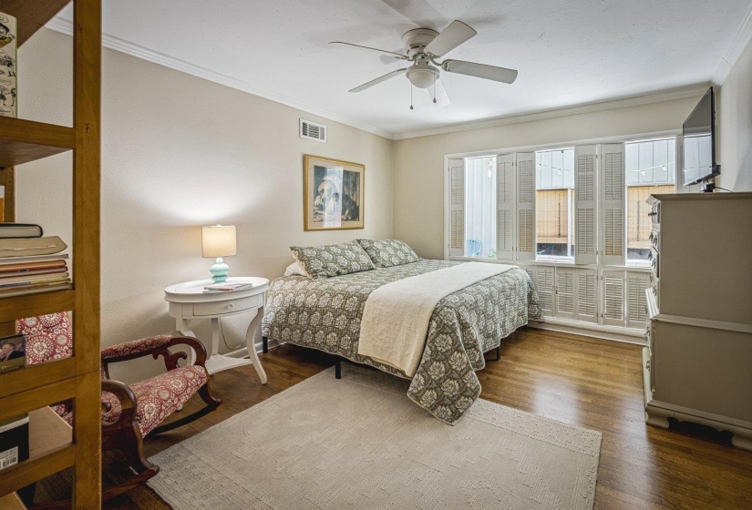Interior room featuring wood-finish flooring, white crown molding, and a ceiling fan with integrated lighting
