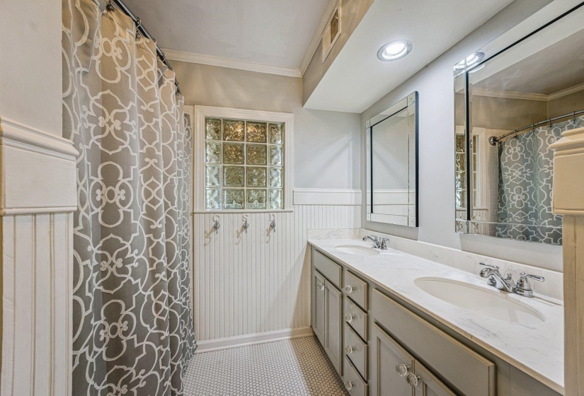 Bathroom featuring dual vanity with undermount sinks, stone countertop, and custom cabinetry