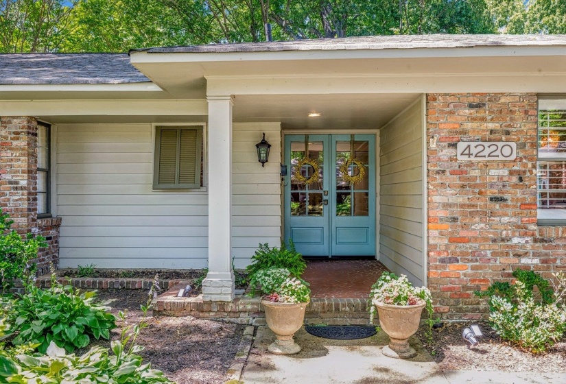 Brick and siding exterior featuring a covered entry, light blue double-entry doors with glass panels, and an exterior wall lantern