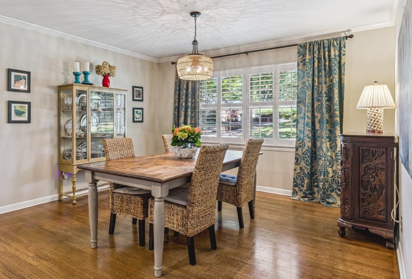 Dining area featuring wood-finish flooring, crown molding, and a decorative light fixture