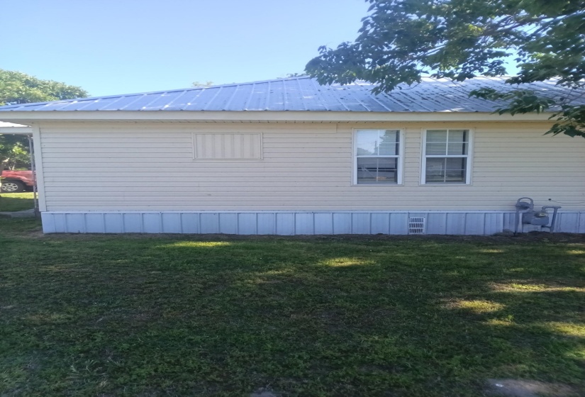 Beige vinyl siding exterior with a pitched metal roof