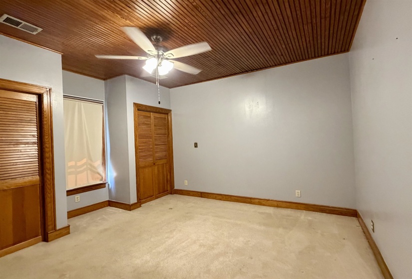 Wood-paneled ceiling with a central ceiling fan and light fixture