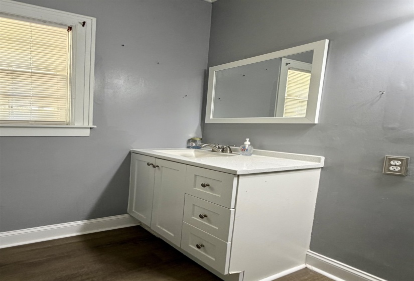White vanity with integrated sink, brushed nickel faucet, and white framed mirror