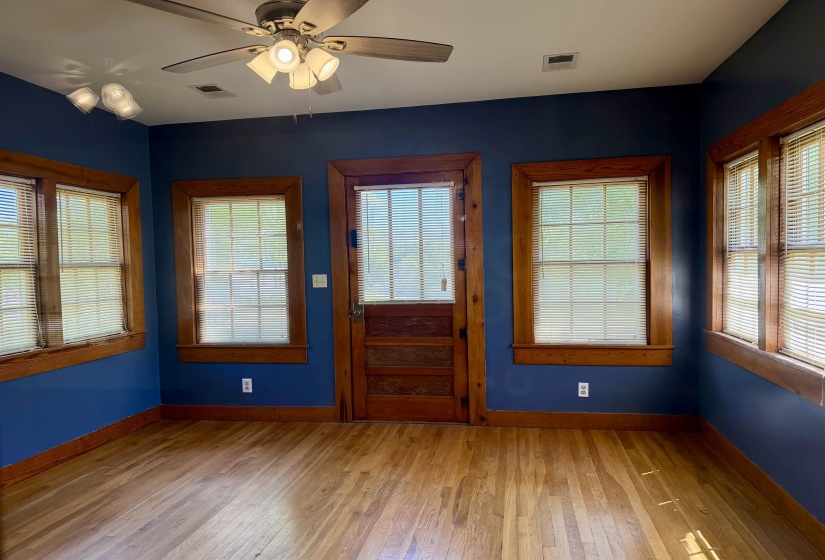 Room featuring wood-finish flooring, wood trim, blue painted walls, and multiple windows with blinds