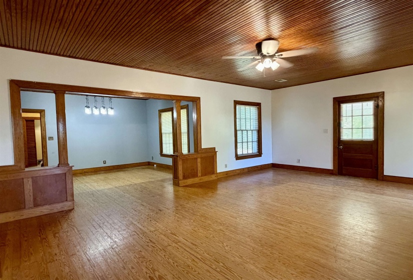 Expansive living area featuring wood-finish flooring, a wood-paneled ceiling, and a ceiling fan with integrated lighting