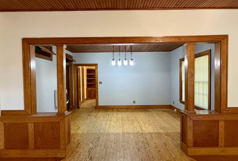Hardwood flooring extends throughout this expansive room, featuring wood-paneled walls and a wood beadboard ceiling