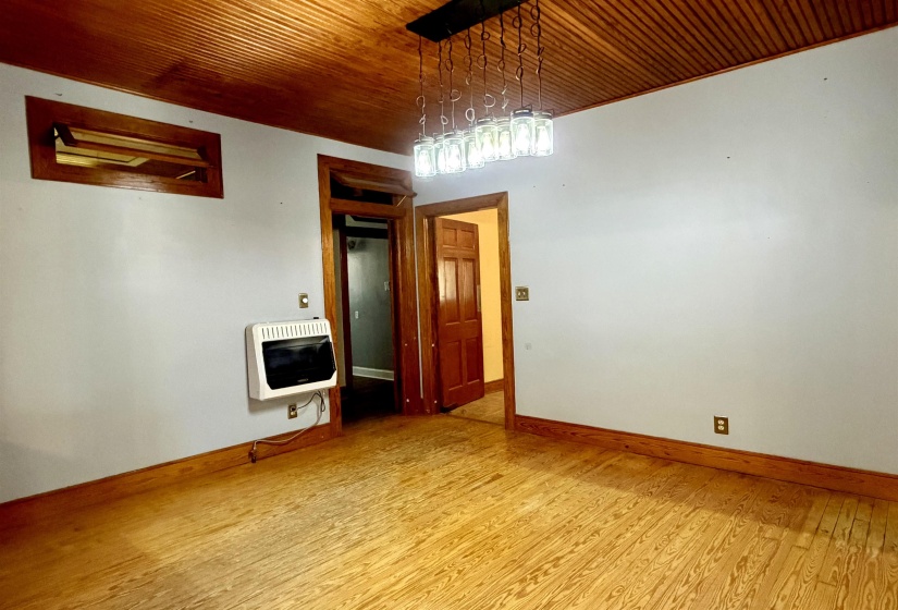 Room featuring wood-finish flooring, white walls, and a warm wood-paneled ceiling