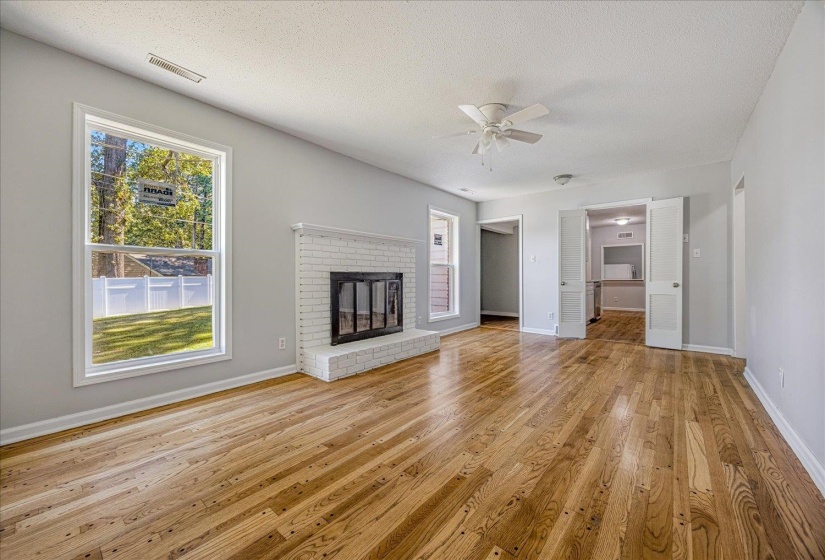 Unfurnished living room featuring a textured ceiling, plenty of natural light, light wood finished floors, and ceiling fan