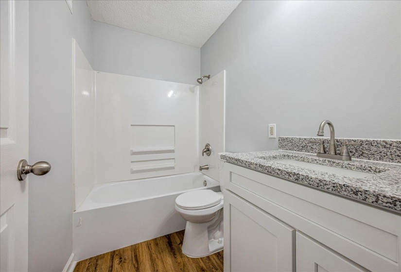 Bathroom with vanity, shower / washtub combination, dark wood-style floors, and a textured ceiling