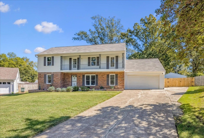 View of front of home with brick siding, concrete driveway, a porch, and a garage