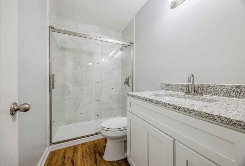 Bathroom with vanity, a stall shower, and dark wood-type flooring