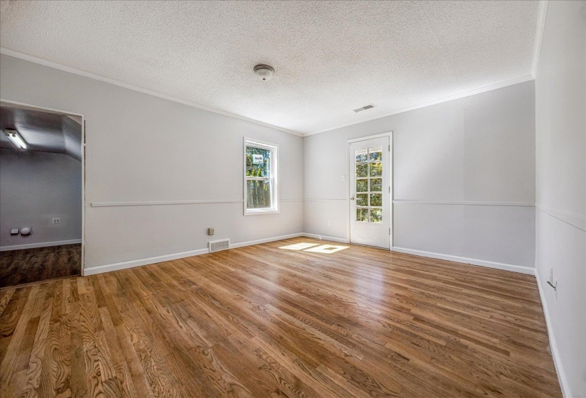 Unfurnished room featuring crown molding, a textured ceiling, and wood finished floors