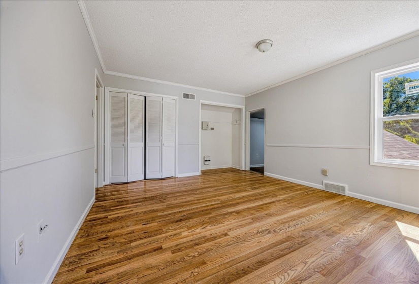 Unfurnished bedroom featuring crown molding, light wood-type flooring, a textured ceiling, and a closet