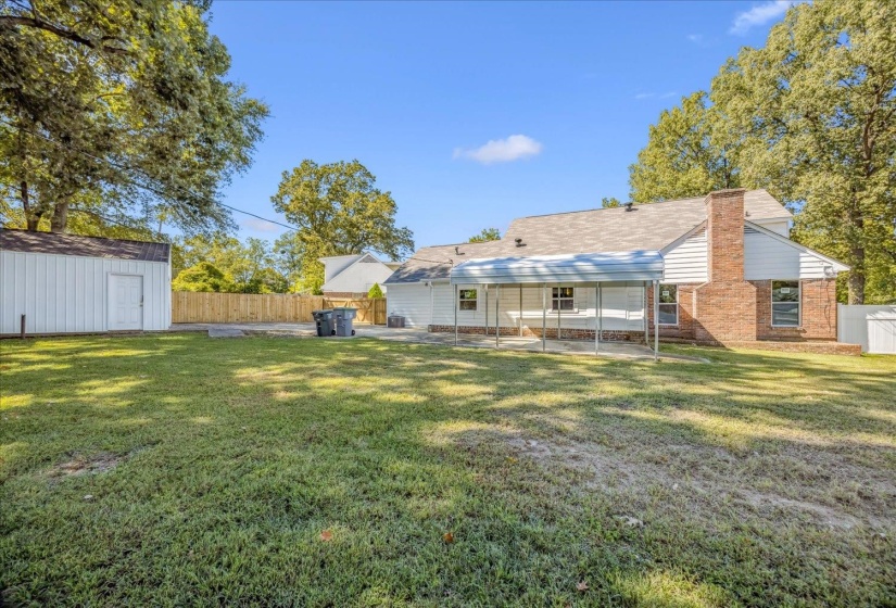 Back of house featuring a patio area, a fenced backyard, brick siding, a chimney, and a storage shed