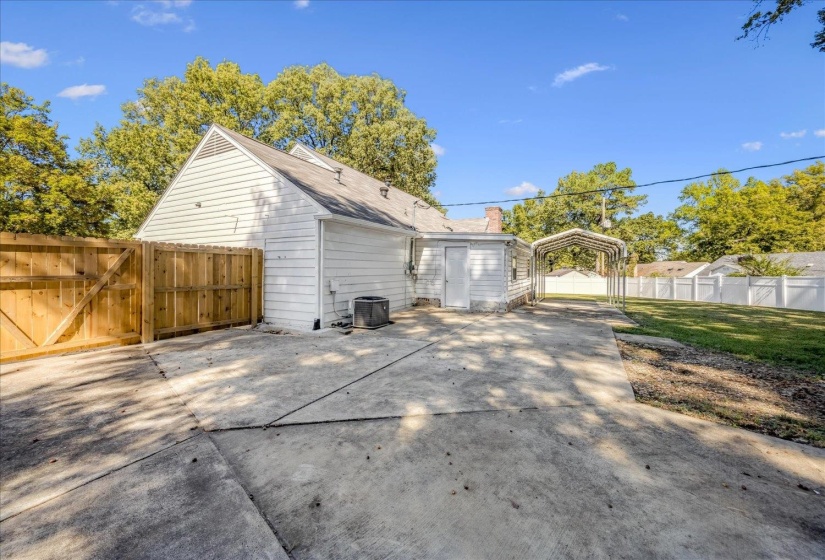 Rear view of house featuring a carport, a gate, driveway, and a chimney