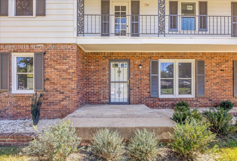 Property entrance with brick siding and a patio area