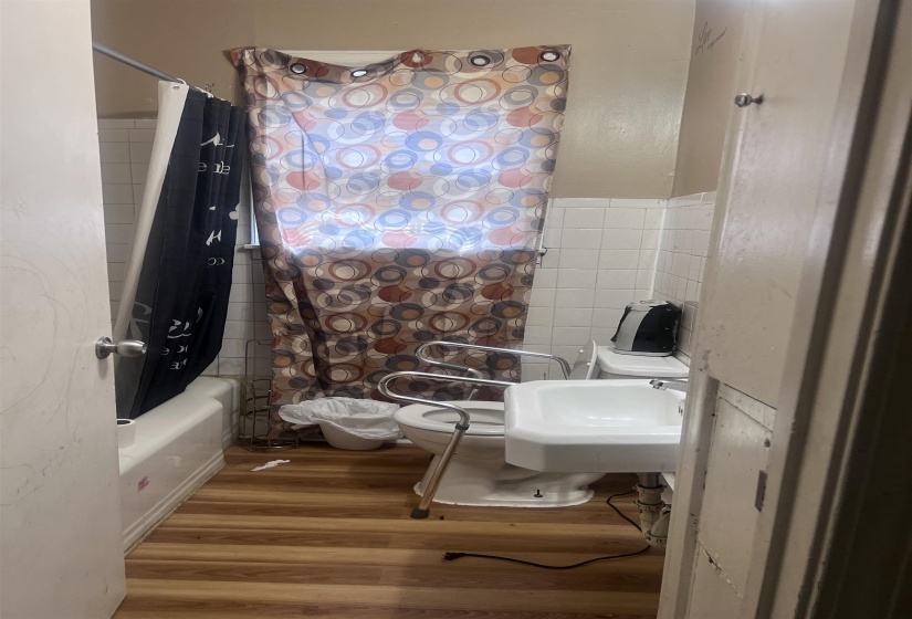 Bathroom featuring a wall-mounted sink, toilet, and a combined tub/shower with white tile surround