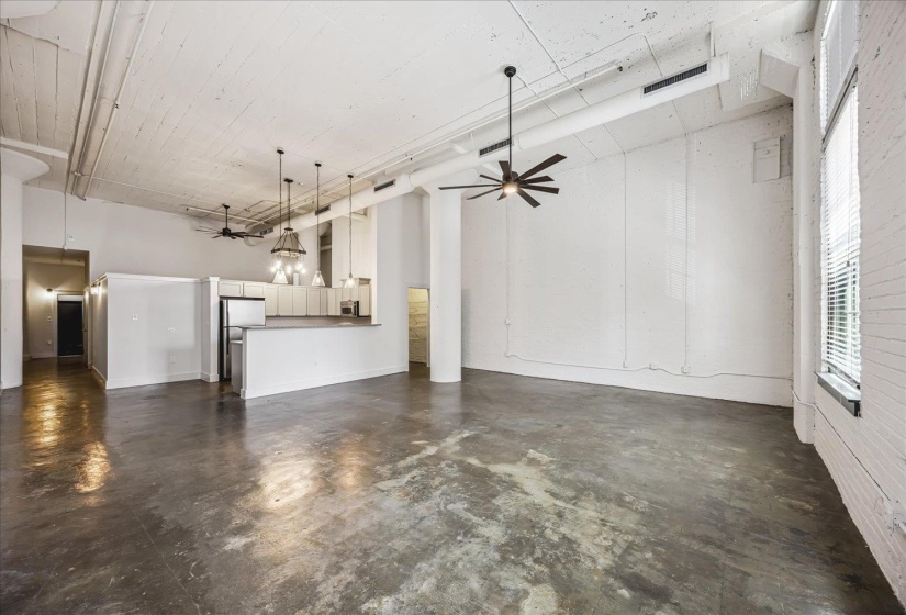 Expansive open-concept living area featuring polished concrete flooring and white painted brick walls