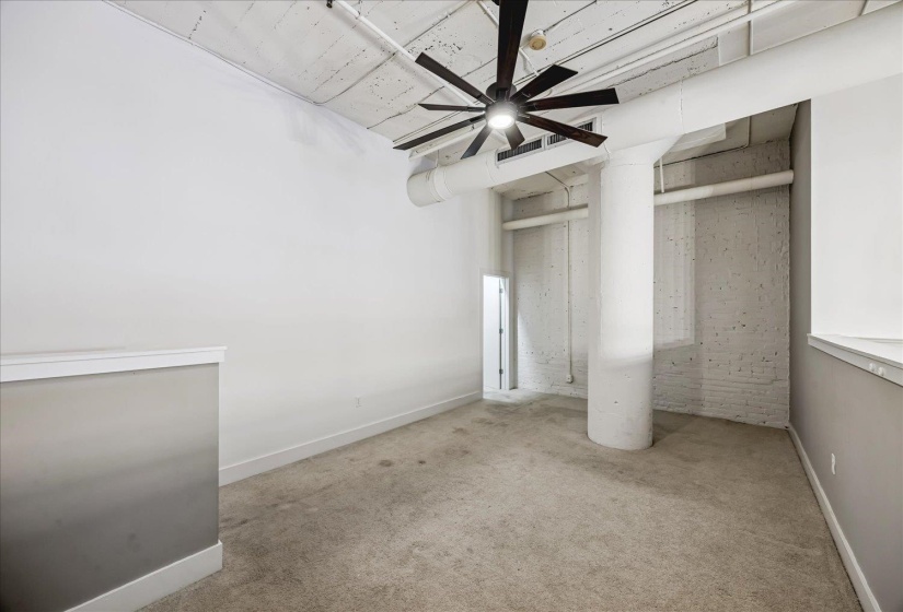 Open-concept room featuring a contemporary ceiling fan, exposed ductwork, and a distinctive concrete column