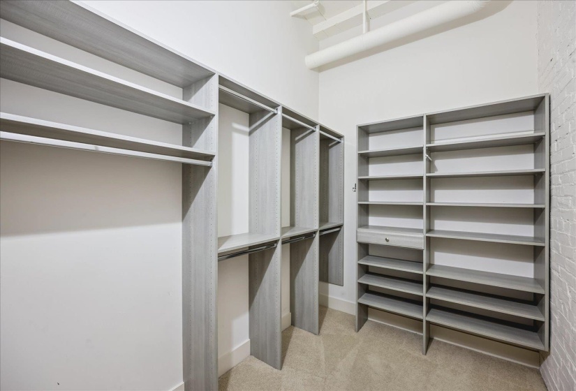 Custom closet system featuring multiple hanging rods, open shelving, and integrated drawer storage