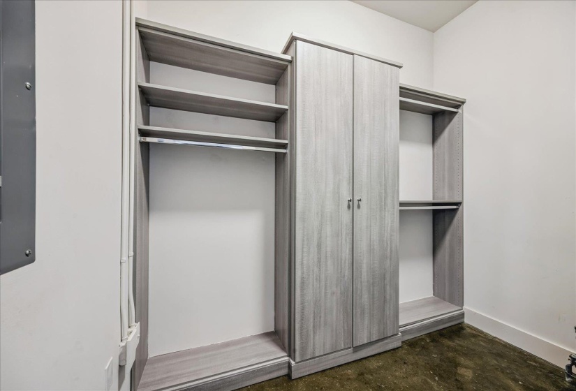 Custom closet system featuring a light wood-finish, open shelving, integrated hanging rods, and a central wardrobe with double doors