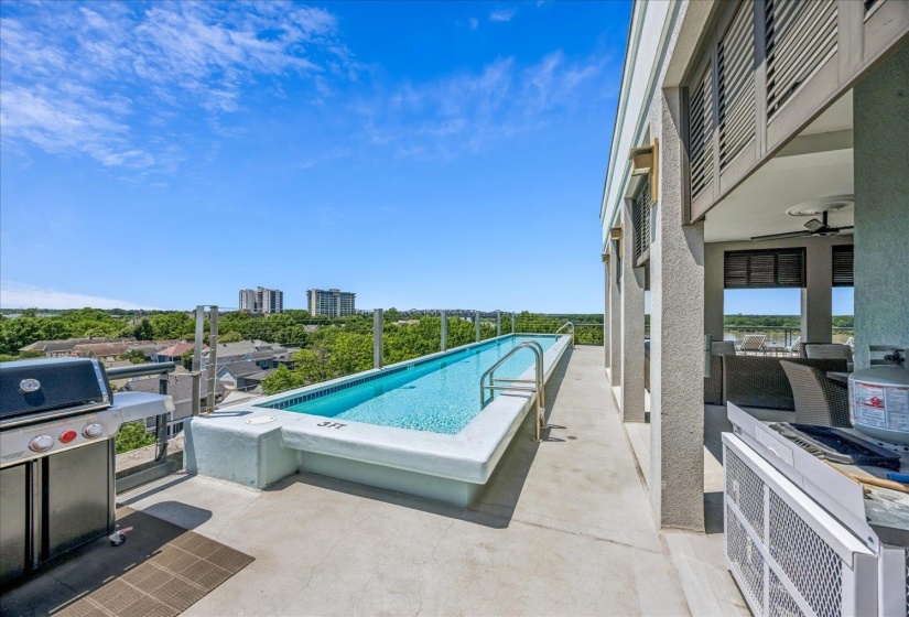 Rooftop terrace with a rectangular plunge pool, surrounding cityscape, and outdoor kitchen area