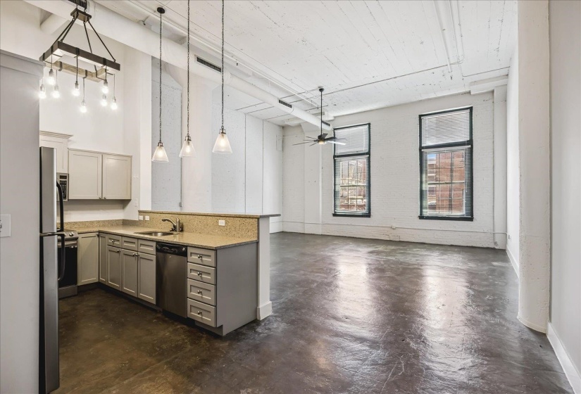 Open-concept living space featuring a kitchen with light-colored cabinetry, stainless steel appliances, and a breakfast bar