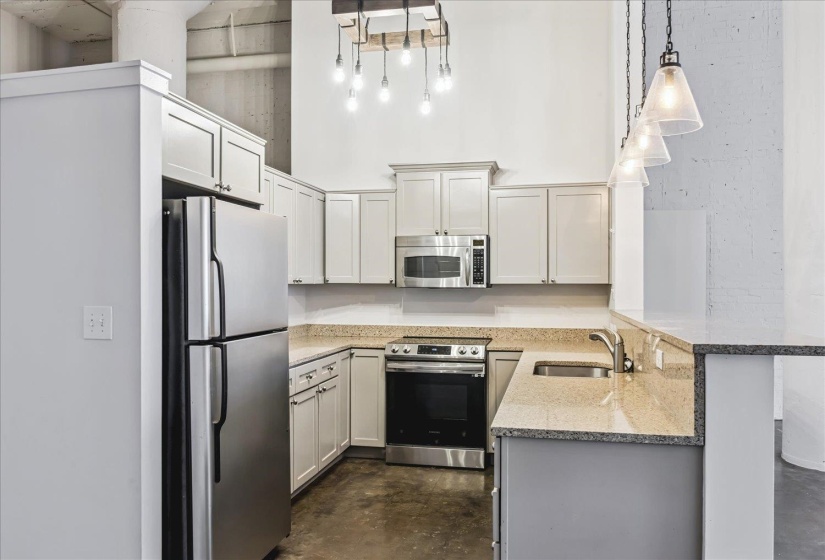 Kitchen featuring stainless steel appliances, light-toned cabinetry, granite-finish countertops, and a double-basin sink