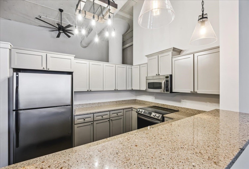 Kitchen featuring light-toned cabinetry, stainless steel appliances, speckled countertops, and an integrated cooktop