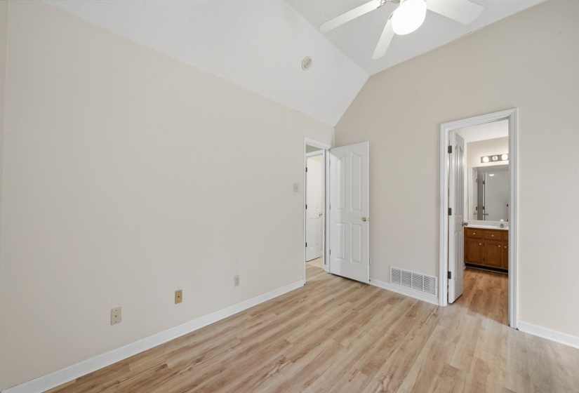 Vaulted ceiling with a ceiling fan, light wood-finish flooring, and light-toned walls
