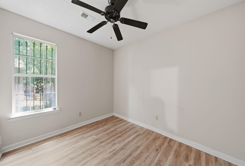 Room featuring light-toned walls, wood-finish flooring, and a ceiling fan with integrated lighting