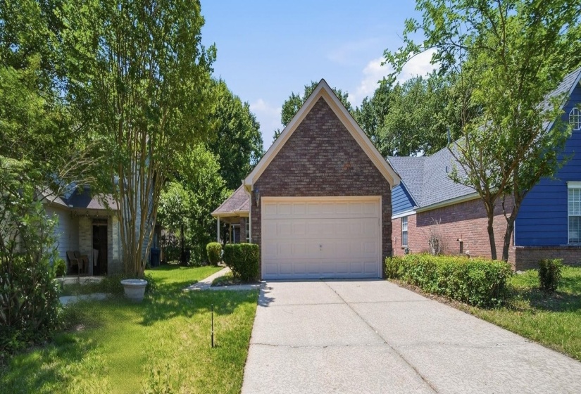 Brick exterior with a peaked roofline, an attached two-car garage, and a concrete driveway