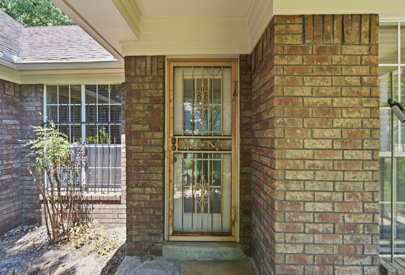 Brick exterior featuring a decorative metal security door and multiple pane windows
