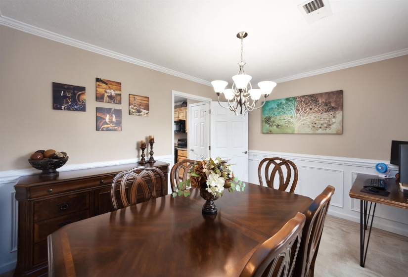 Dining area featuring crown molding, wainscoting, and a five-light chandelier