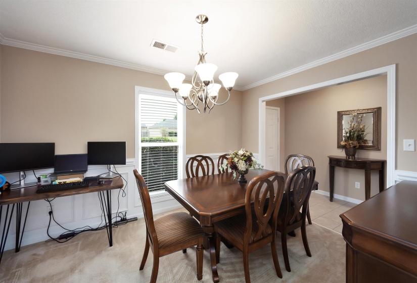 Dining area featuring a contemporary chandelier, crown molding, and wainscoting