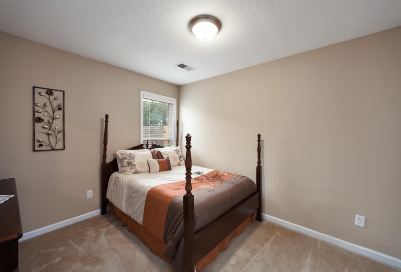 Carpeted bedroom with neutral wall tones and white baseboards