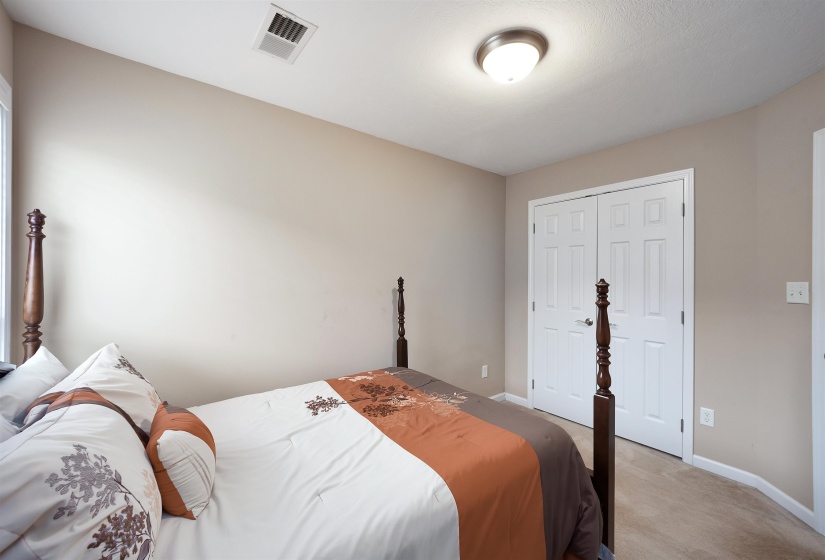 Neutral-toned room featuring a window, built-in closet with white bifold doors, and neutral carpet flooring