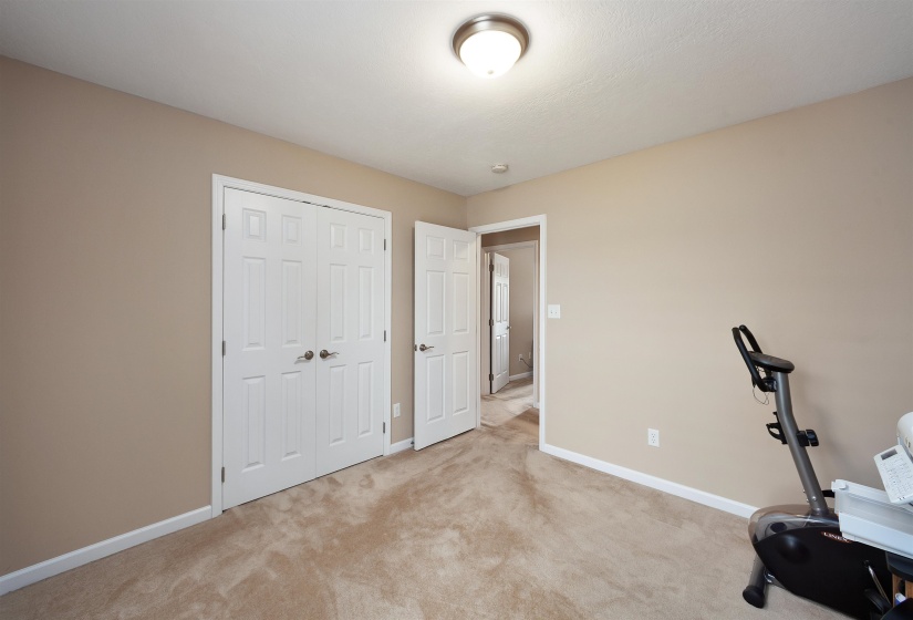 Carpeted room featuring neutral-toned walls, white baseboards, and a flush-mount ceiling light