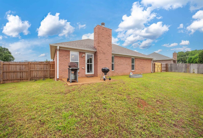 Expansive backyard featuring a red brick exterior, a concrete patio, and a wood privacy fence
