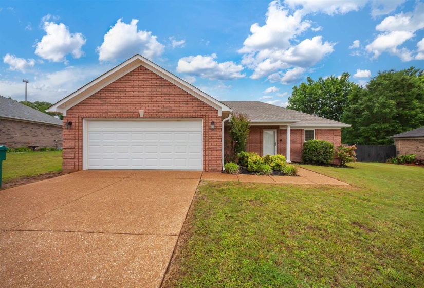 Brick exterior featuring an integrated garage, covered front entry, and a concrete driveway