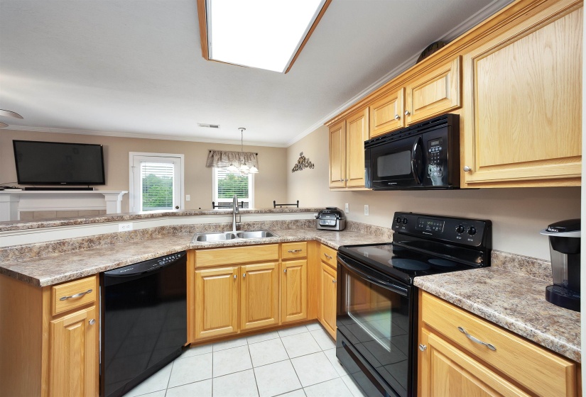 Kitchen featuring wood cabinetry, stone-look countertops, and white tile flooring