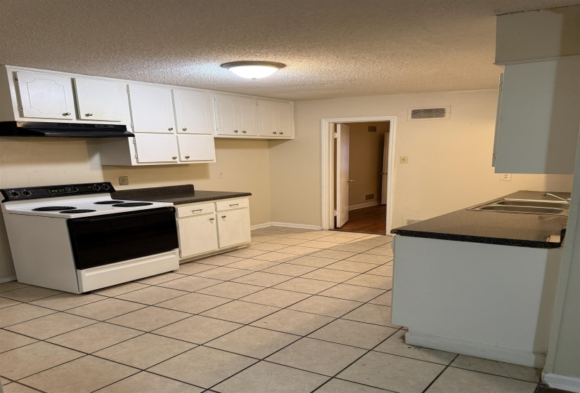 Kitchen featuring white cabinetry, dark countertops, a white electric range, and tile flooring