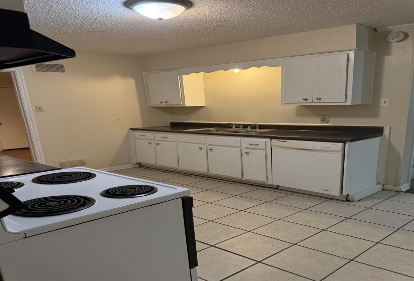 Kitchen featuring white cabinetry, dark countertops, a built-in dishwasher, and a white electric range