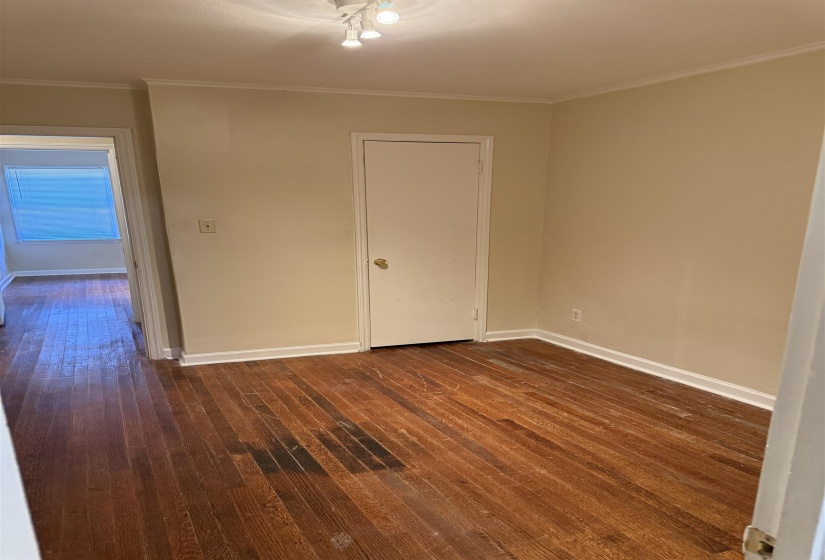 Room featuring wood-finish flooring, neutral wall tones, white trim, and a track lighting fixture