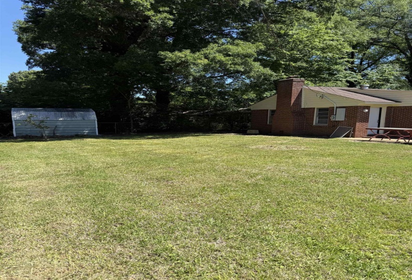 Spacious backyard featuring a brick exterior, chimney, and a separate storage shed