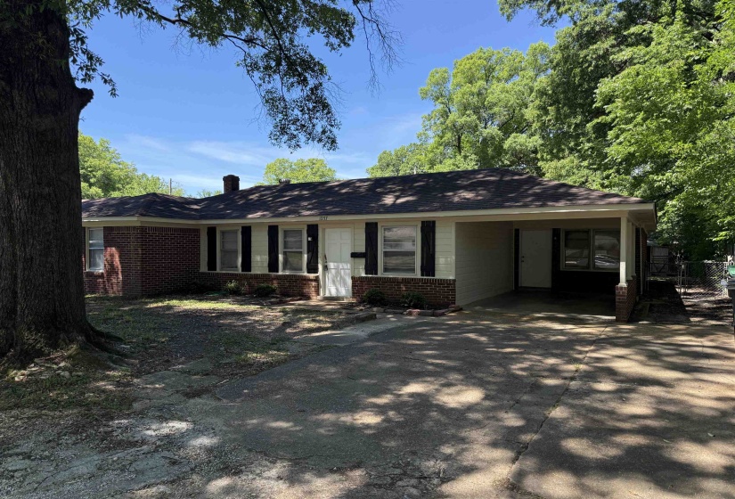Ranch-style residence featuring brick and siding exterior, a covered carport, and mature trees