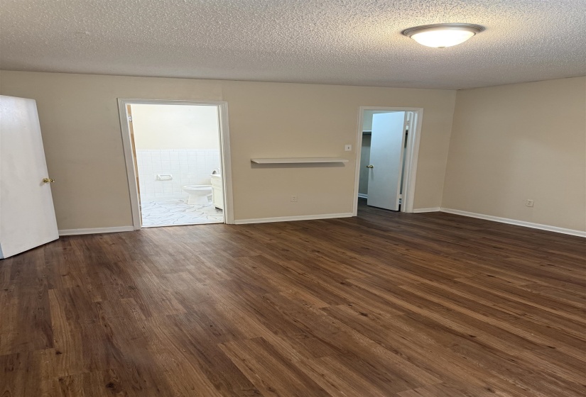 Wood-finish flooring throughout, featuring a cream wall palette, white baseboards, and a semi-flush ceiling light
