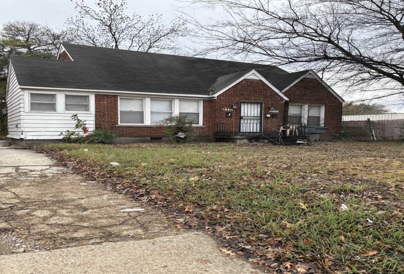 View of front of home featuring brick siding and roof with shingles