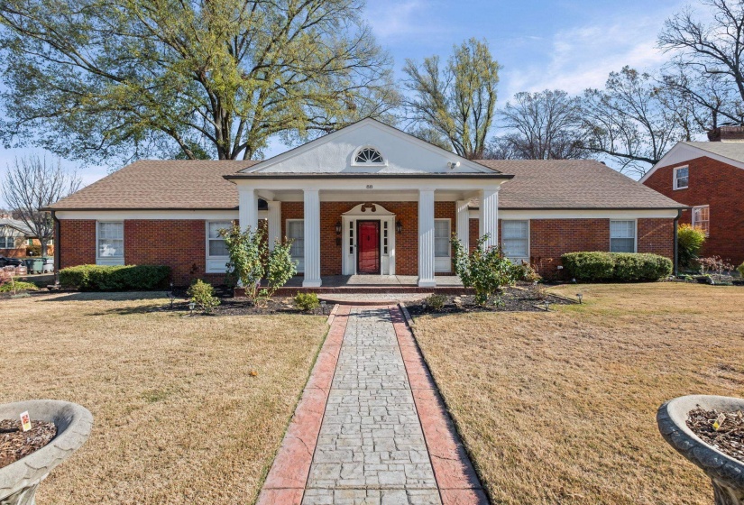 Neoclassical home featuring covered porch, brick siding, a front lawn, and a shingled roof